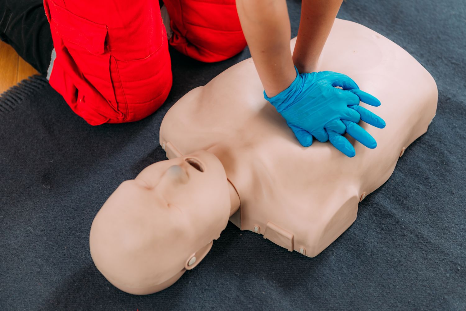Person with blue gloves training in CPR on a dummy